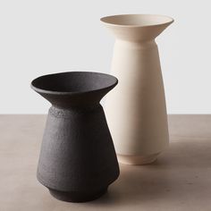 two black and white vases sitting next to each other on top of a table