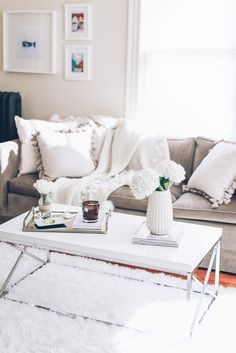 a coffee table with flowers on it in front of a couch