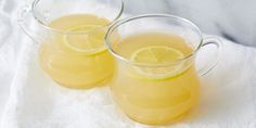 two glasses filled with lemonade sitting on top of a white cloth covered tablecloth