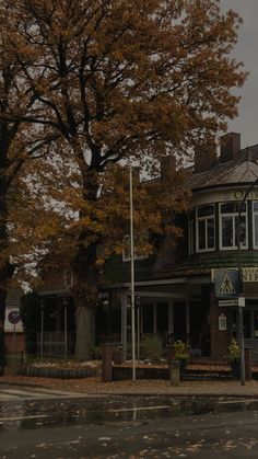 an old fashioned building on the corner of a street in front of a large tree