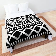 a black and white bed spread on top of a wooden floor