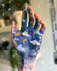 a person's hand covered in blue and white paint with stars and moon on it