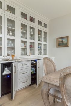 a dining room table and chairs in front of a built - in wine cooler with glass doors