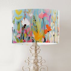 a lamp that is on top of a wooden stand with a flower print shade over it