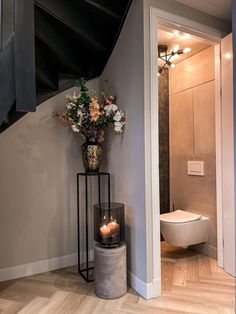 a vase filled with flowers sitting on top of a metal stand next to a toilet