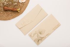 two envelopes with flowers on them next to a straw hat and other items that include a wooden handle