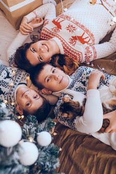 three young women laying on the floor with christmas decorations and presents in front of them