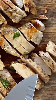 sliced up chicken on a cutting board with a knife and seasoning next to it