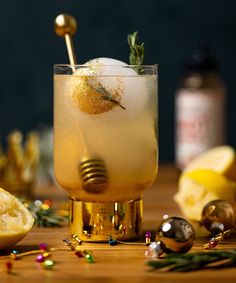 a glass filled with ice and lemon on top of a wooden table next to other items