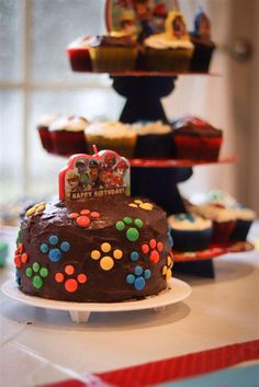 there is a chocolate cake on the table with other cupcakes in the background