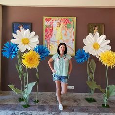 a woman standing in front of three fake flowers