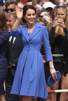 a woman in a blue dress waves to the crowd