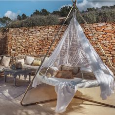 a hammock is set up in front of a stone wall and patio furniture