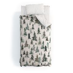 an unmade bed with trees printed on it