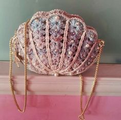 a crocheted purse sitting on top of a window sill next to a chain