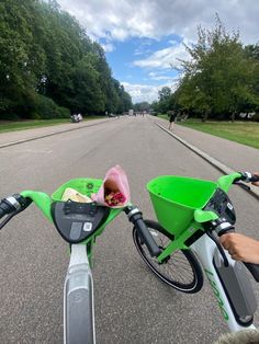 a person riding a bike down a street next to a green bin filled with food