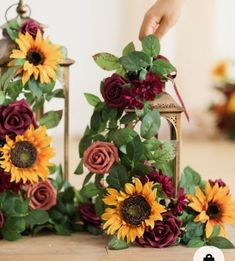 sunflowers and other flowers are arranged on the floor next to a small lantern