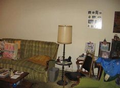 a living room filled with furniture next to a lamp and pictures on the wall behind it