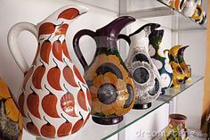 several colorful vases are displayed on glass shelves