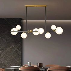 a dining room table with chairs and lights hanging from it's ceiling over it