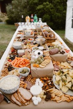 a long table filled with lots of food on top of a grass covered field next to trees