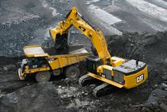 an excavator is dumping coal into a dump truck