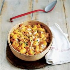 a wooden bowl filled with macaroni and cheese on top of a table next to a white towel