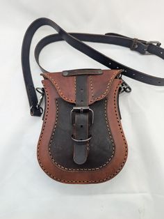 a brown and black leather shoulder bag on a white background, with the strap down