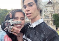 a man and woman posing for a photo in front of a castle with a fake toothbrush