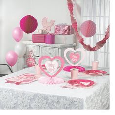 a table set up with pink decorations and heart - shaped paper cutouts for valentine's day