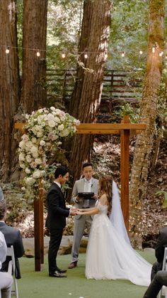 a bride and groom exchanging vows at their outdoor ceremony in the woods with string lights overhead