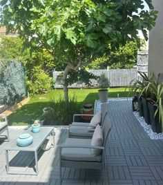 an outdoor patio with chairs, table and potted trees