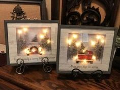 two framed pictures with christmas lights on them sitting on a table next to each other