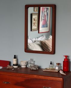 a dresser with a mirror above it and various items on the top shelf next to it