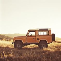 an orange truck parked in the middle of a field