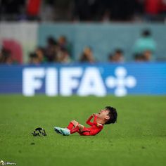 a soccer player laying on the ground with his head in his hands while looking up