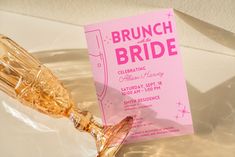 a pink bridal party card sitting on top of a glass vase filled with champagne