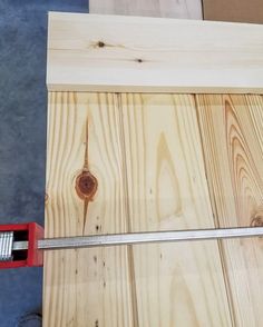 a piece of wood is being cut with a pair of scissors and a tape measure