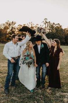 a group of people standing around each other in a field with hats on their heads