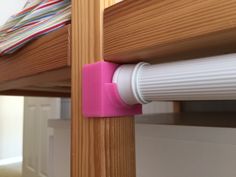 a close up of a pink handle on a wooden bunk bed with a striped curtain behind it