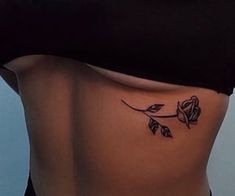 a woman's stomach with a rose tattoo on her lower side ribcage