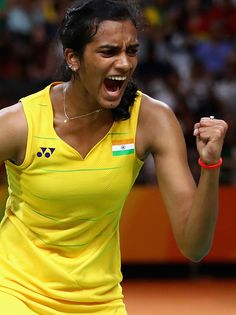 a woman holding a tennis racquet in her right hand and yelling into the air