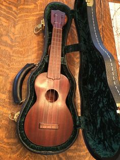 an ukulele in its case on the floor with it's strap open