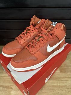 a pair of orange nike sneakers sitting on top of a red box with white outs