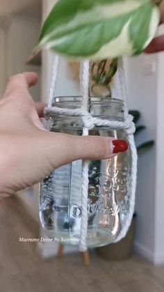 a hand holding a glass jar filled with water