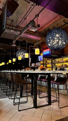 a bar with chairs and lights hanging from the ceiling