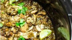 a slow cooker filled with meat, mushrooms and cilantros on the side