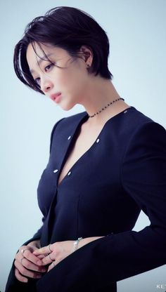 a woman in a black shirt is holding her hand on her hip and looking down