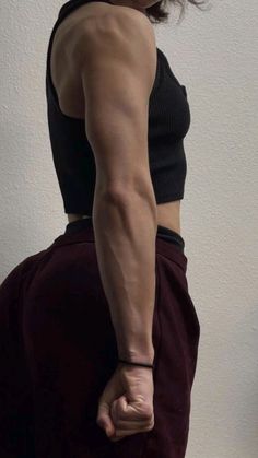 a woman standing in front of a white wall with her back turned to the camera