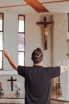 a man standing in front of a crucifix with his arms spread out